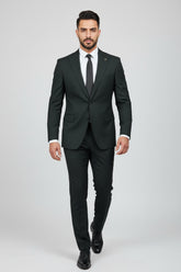 Man wearing dark green tailored two-piece suit with peak lapels and black tie.